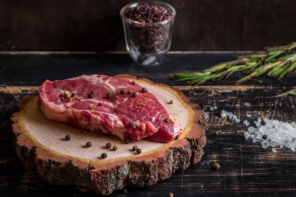 Bistecca di carne succosa cruda su fondo di legno scuro pronta per essere arrostita — Foto Stock