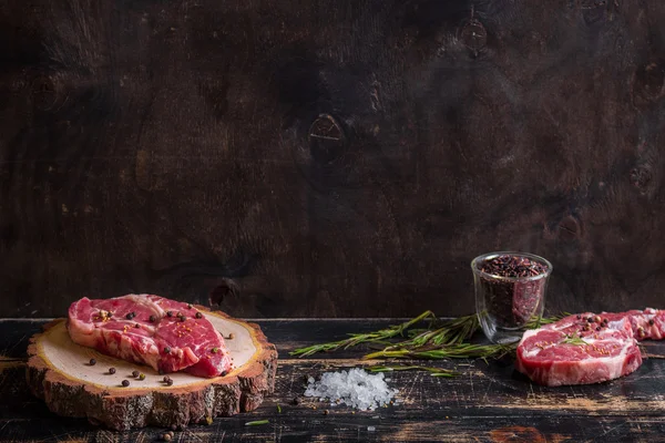 Rohe saftige Fleischsteak auf dunklem Holzhintergrund bereit zum Braten — Stockfoto