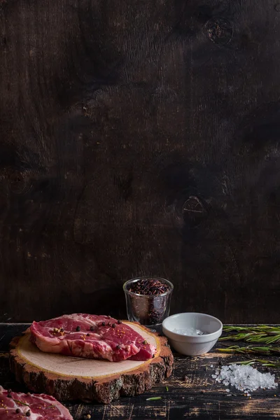 Bifteck de viande cru juteux sur fond de bois foncé prêt à rôtir — Photo