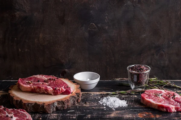 Bistecca di carne succosa cruda su fondo di legno scuro pronta per essere arrostita — Foto Stock