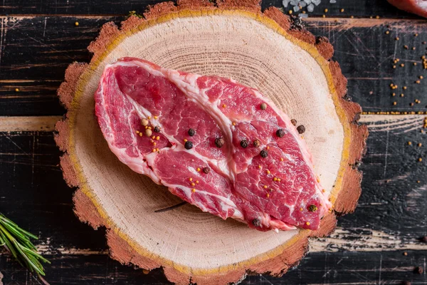 Bife de carne suculento cru no fundo de madeira escura pronto para assar — Fotografia de Stock