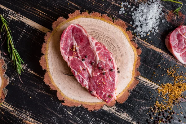 Syrové maso šťavnaté steaky na tmavé dřevěné pozadí připraveno k pečení — Stock fotografie