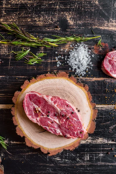 Bife de carne suculento cru no fundo de madeira escura pronto para assar — Fotografia de Stock