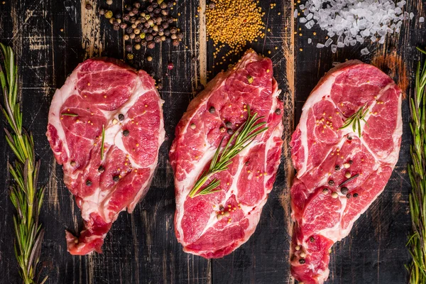 Syrové maso steak na tmavé dřevěné pozadí připraveno k pečení — Stock fotografie