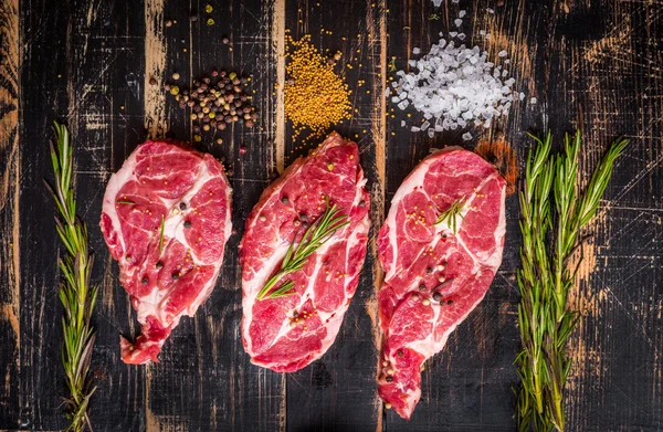 Syrové maso steak na tmavé dřevěné pozadí připraveno k pečení — Stock fotografie