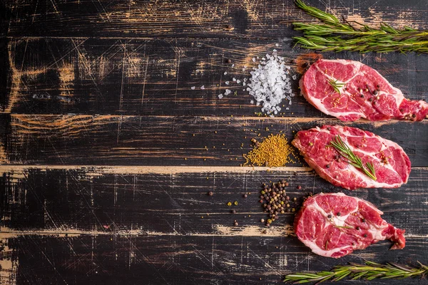 Bistecca di carne cruda su fondo di legno scuro pronta per essere arrostita — Foto Stock