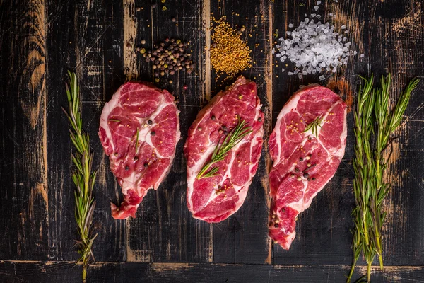 Bife de carne crua no fundo de madeira escura pronto para assar — Fotografia de Stock