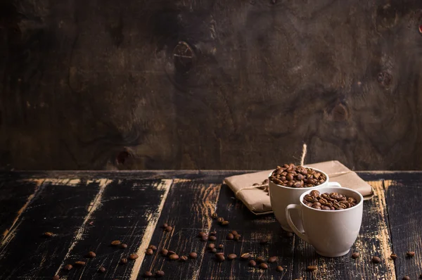 Fincan kahve çekirdekleri, koyu ahşap arka plan ile
