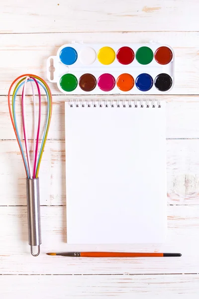 Sketch pad with paints, brush, whisk and tablet — Stock Photo, Image