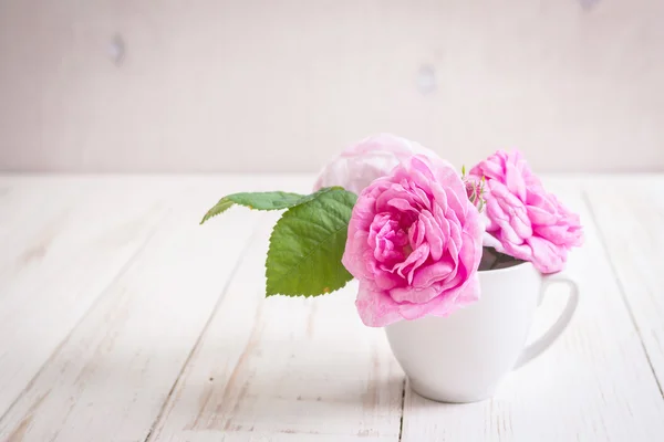 Rosas de té rosadas sobre un fondo de madera blanca — Foto de Stock