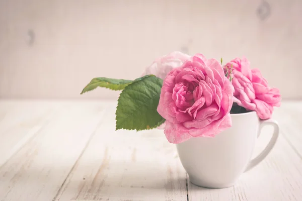 Rosas de té rosadas sobre un fondo de madera blanca — Foto de Stock