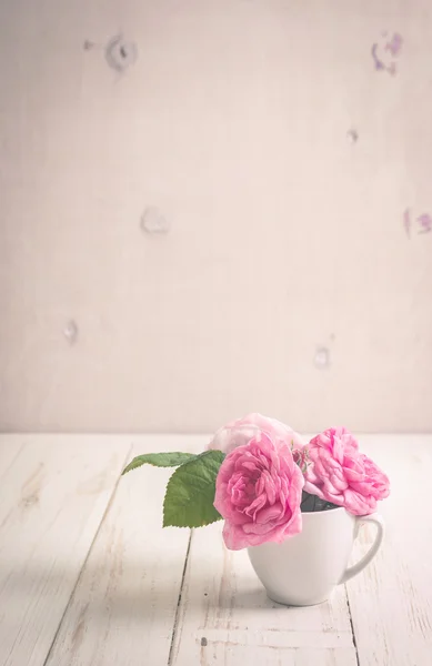 Rosas de té rosadas sobre un fondo de madera blanca — Foto de Stock