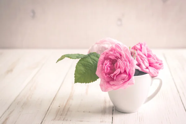 Roses de thé rose sur fond de bois blanc — Photo