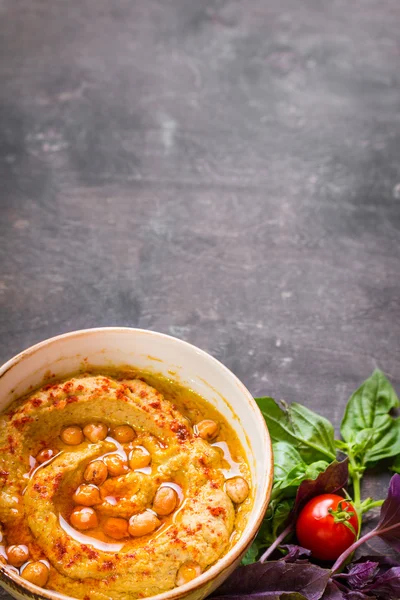 Hummus em uma chapa com tomates de cereja e ervas em um woode escuro — Fotografia de Stock