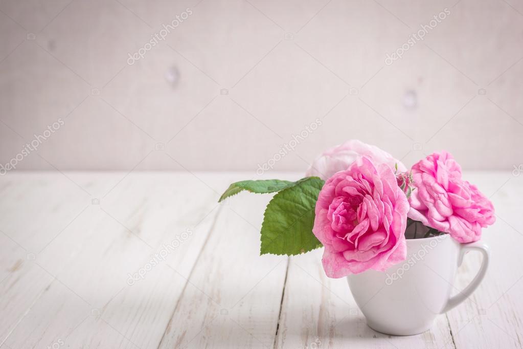 Pink tea roses on a white wooden background