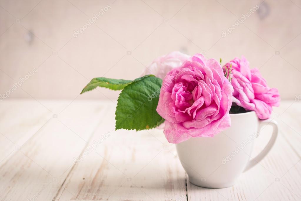 Pink tea roses on a white wooden background