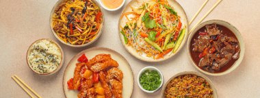 Çeşitli Çin yemekleri, tatlı ve ekşi tavuk, soslu sığır eti, erişte, kızarmış pirinç, salata ve ahşap çubuklar. Çin ya da Asya restoranı konsepti