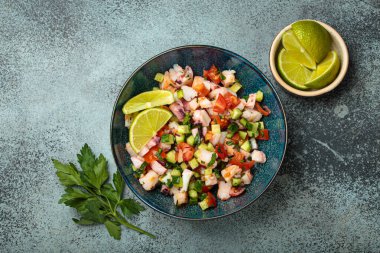 Taze ve canlı Peru deniz ürünleri ceviche ile karides, ahtapot, domates, salatalık ve maydanoz, yukarıdaki taştan bir arka planda limonla servis edilmiş, Peru yemeği.