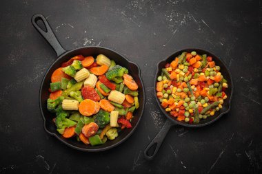 Sağlıklı yemek, canlı donmuş sebzeler ve koyu bir arka planda dökme demir tavalar hazırlamak.