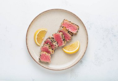 Susamlı ve limon dilimli kurutulmuş ahi ton balığı, sağlıklı, gurme deniz ürünleri için taze pembe dilimler Asya usulü Asya usulü aperatif yemeği.