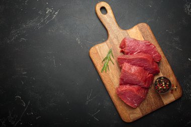 Tahta kesme tahtasındaki çiğ biftekler taze biberiyeyle pişirilmeye hazır ve metin için bir karışım karabiberli mısır.