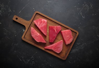 Taze kesilmiş ton balığı bifteği pişirmeye hazırlanıyor, tahtadan dilimler.