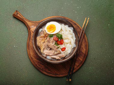 İçinde pirinç eriştesi, yavaş pişmiş ördek, haşlanmış yumurta, kırmızı biber ve kişniş olan tuzlu ramen çorbası.