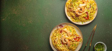 İki tabak Tayland eriştesi, karides, fıstık, limon, biber ve yeşil zemin üzerinde taze soğan ve yemek çubukları ve kabın içindeki malzemelerle. Geleneksel Tayland yemeği, metin için alan