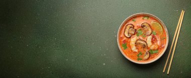 Karides, mantar, limon ve kişniş karışımlı lezzetli Tom çorbası mavi arka planda yemek çubuklarıyla servis edilen Tayland aromalı geleneksel bir yemektir.