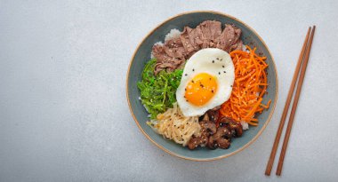 Bibimbap, haşlanmış pirinçli otantik Kore yemeği omlet, sığır eti, renkli sebzeler, açık arkaplanda geleneksel Kore yemeği, kopyalama alanı.