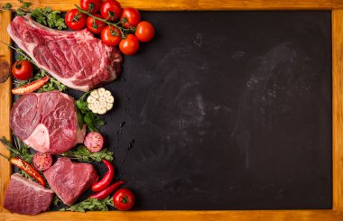 Çiğ et biftek kavurma için hazır karanlık bir arka plan üzerinde