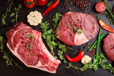 Raw meat steaks on a dark background ready to roasting clipart