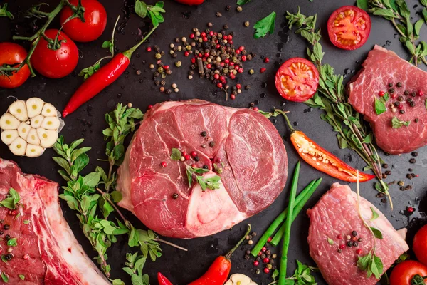 Bifes de carne crua em um fundo escuro pronto para assar — Fotografia de Stock