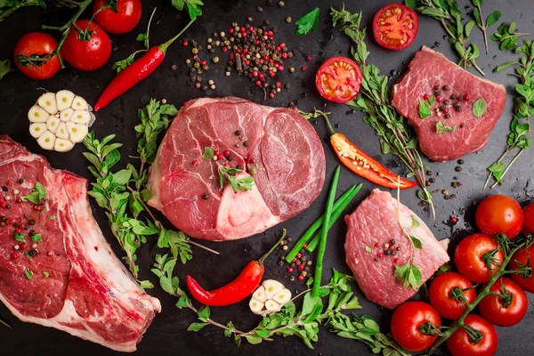 Raw meat steaks on a dark background ready to roasting — Stock Photo, Image