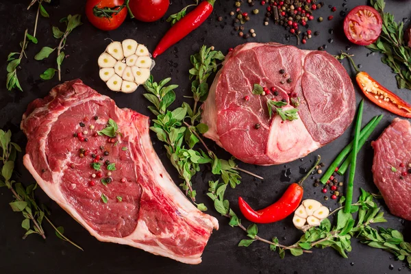 Bifes de carne crua em um fundo escuro pronto para assar — Fotografia de Stock