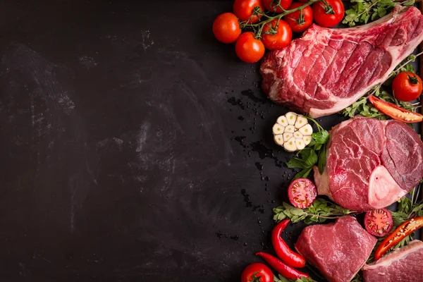 Bistecche di carne cruda su fondo scuro pronte alla tostatura — Foto Stock