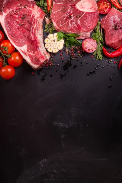 Bifes de carne crua em um fundo escuro pronto para assar — Fotografia de Stock