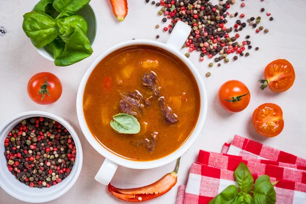 Soupe de tomates avec viande dans un bol blanc sur un backgrou en bois blanc — Photo