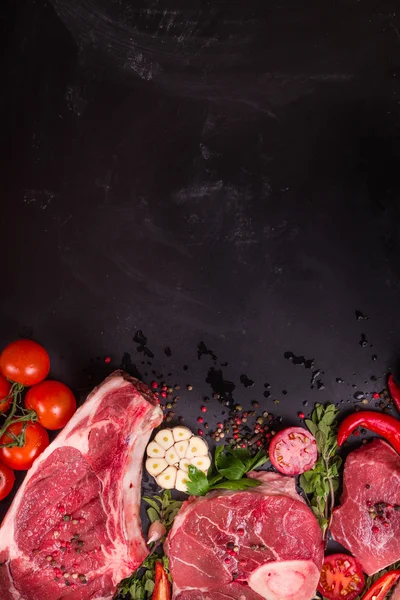 Стейки из сырого мяса на тёмном фоне, готовые к жарке — стоковое фото