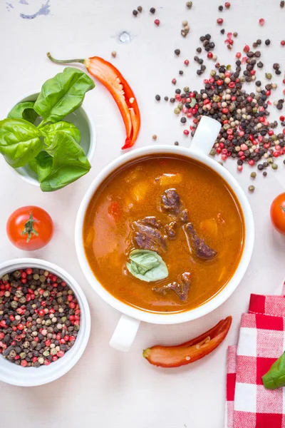 Sopa de tomate con carne en un tazón blanco sobre un fondo de madera blanca — Foto de Stock