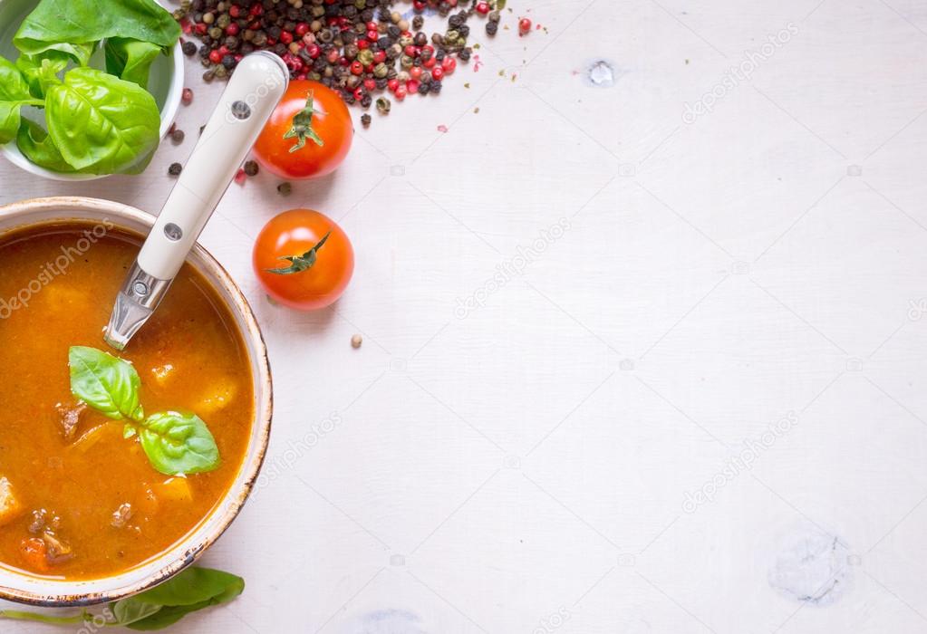 Tomato soup with meat in a white bowl on a white wooden backgrou