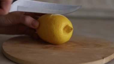 Tahta bir kesme tahtasının üzerinde bıçakla ikiye bölünmüş bir limon görüntüsü. Limon dilimliyorum. Ekşi meyve. Soğuk tedavi.