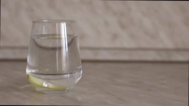 İkinci dilim limon yavaş çekimde bir bardak suya düşer. İkinci limon dilimi yavaşça berrak bir bardak suya düşer. Bardaktaki bir dilim limon güzelce ve yavaşça suya batar.