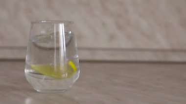 Bir dilim limon yavaş çekimde bir bardak suya düşer. Bir dilim limon yavaşça bir bardak içme suyuna atılır. Bir dilim limon yavaşça bir bardak suya düşer. Metin için yer