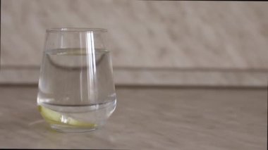 İkinci bir limon dilimi bir bardak suya düşer. İkinci bir limon dilimi şeffaf bardağa suyla düşer. Bardaktaki bir limon dilimi güzelce düşer. Metin için yer.