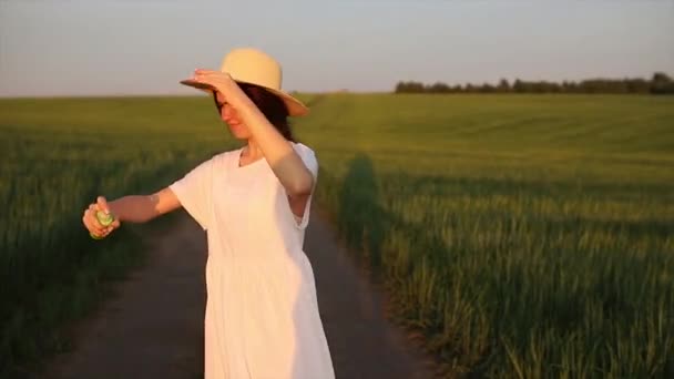 Молодая Девушка Стоит Зеленом Поле Белом Платье Шляпе Опрыскивает Себя — стоковое видео