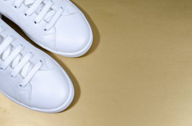 Sarı arka planda izole edilmiş beyaz spor ayakkabılar..