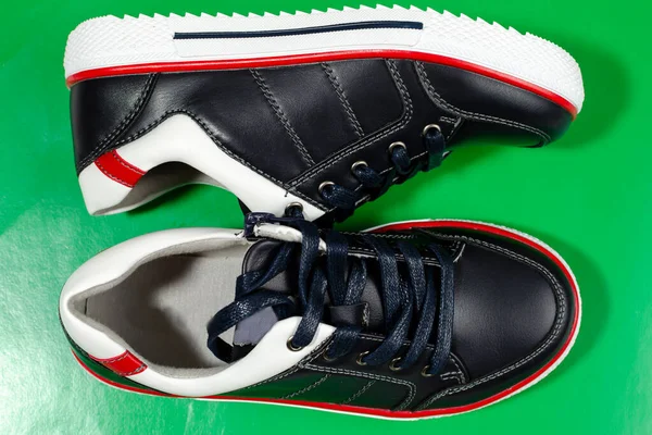 Yeşil Zeminde Izole Edilmiş Beyaz Tabanlı Siyah Spor Ayakkabılar — Stok fotoğraf