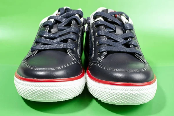 緑色の背景に白い靴底が孤立した黒いスニーカー — ストック写真