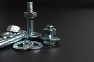 siyah arkaplana karşı birkaç metal cıvata ve fındık